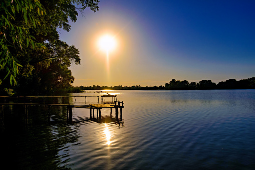Pier juts out into large lake at sunset providing peaceful and picturesque view.
