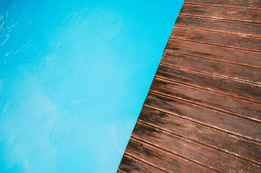 Empty wooden deck with blue swimming pool