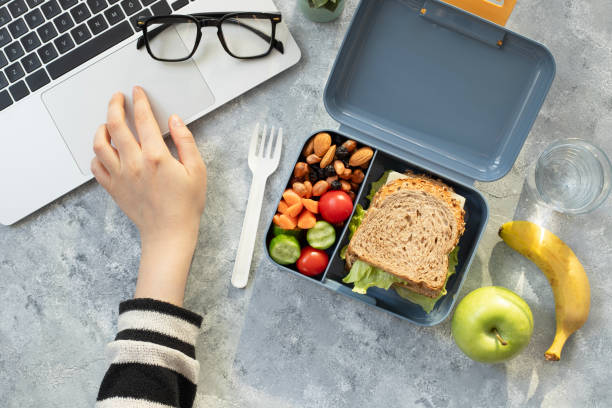 healthy business lunch at workplace. sandwich, vegetables, fruid and water lunch box on working desk with laptop, glasses. - sandwich turkey lunch table foto e immagini stock