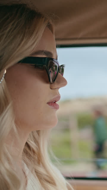 Attractive lady driver riding auto in sunglasses closeup. Girl driving vertical
