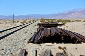 Rusty railroad tracks piled up in the desert along the train tracks