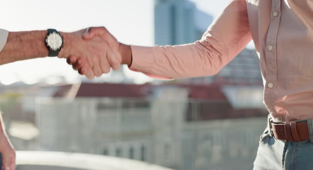 Business people, handshake and partnership in city for b2b, teamwork or greeting in urban town. Businessman or employees shaking hands on building rooftop or outdoor balcony for agreement or deal