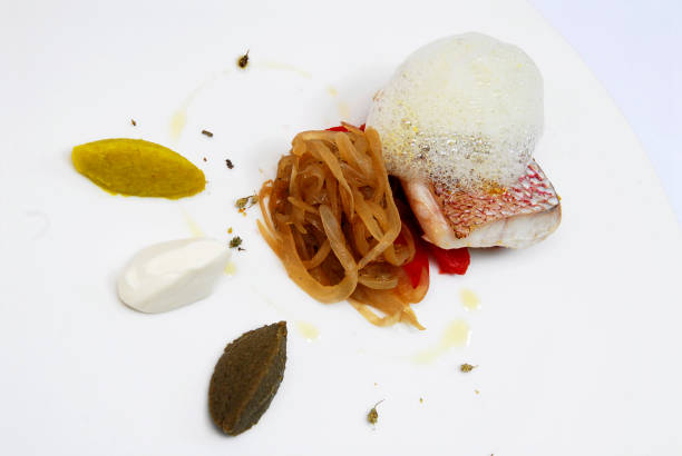 fish with skin caramelized onion and bell pepper covered with foam close up view