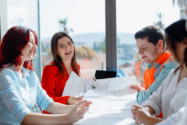 istock Productive Collaboration: Architects and Engineers Engaged in a Positive and Happy Meeting in a Modern Office Board Room, Bathed in Sunlight. Working with Laptops and Blueprint Projects for Efficient Planning 2008766623