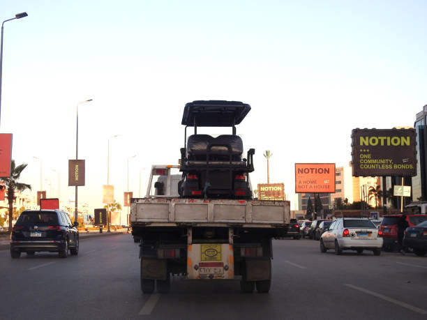 a tow recovery transporter hydraulic flatbed truck moving electric golf cart moving in the street, golf buggy, cart or car is a small motorized vehicle - truck driver ストックフォトと画像