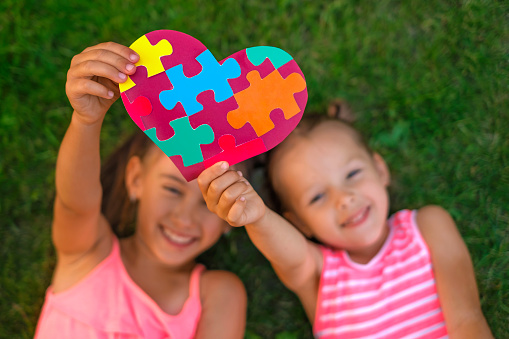 Friendly Girls show a close-up of a puzzle heart as a sign of support for people with autism spectrum disorder.