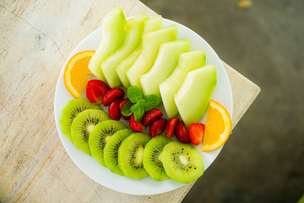mixed fruit plate containing melon, strawberries, oranges and kiwi.