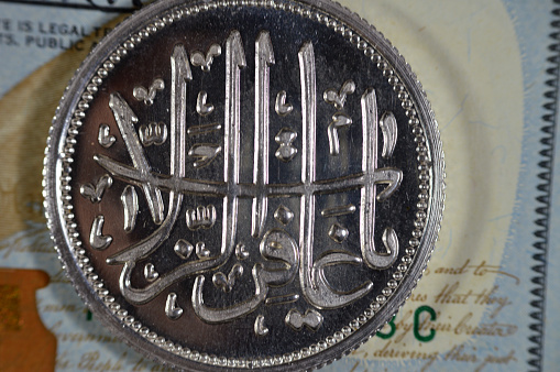 Translation of the Arabic text (O forgiver of transgressions), Islamic pure silver ounce coin, The price of silver is driven by speculation, supply and demand, with USD American dollars in the Image, selective focus