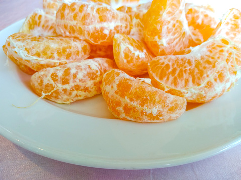 Penang, Malaysia\n\nClose up of mandarin oranges that I have peeled open. And then placed in a heap, on a white plate. Copy space available