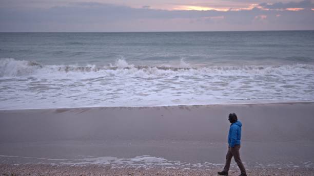 istock Man walking by the sea at sunrise. copy space 2008905009