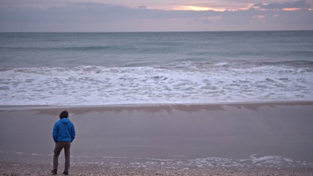 istock Man walking by the sea at sunrise. copy space 2008905011