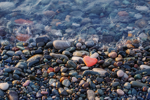 red stone in  shape of heart on  beach by  sea