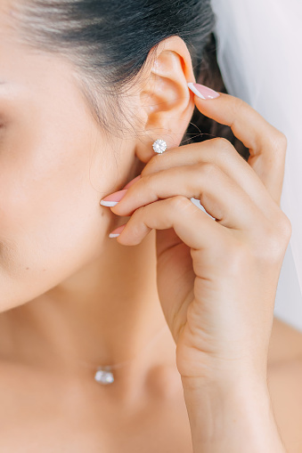 bride puts on a diamond earring for wedding celebrations