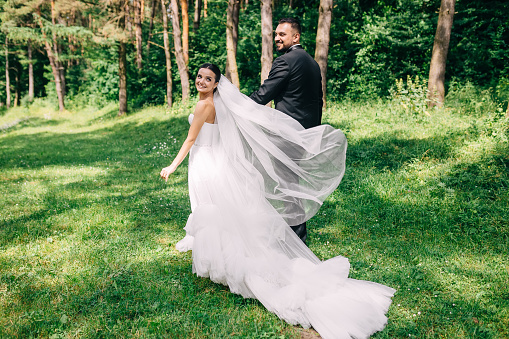 newlyweds bride and groom walk on the grass and rejoice on a happy wedding day.