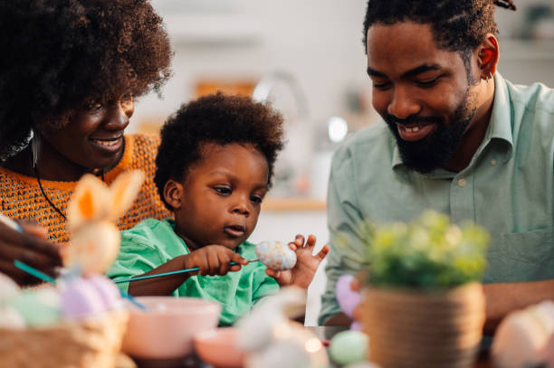 istock Young black family is having fun painting easter eggs on holiday. 2008915527
