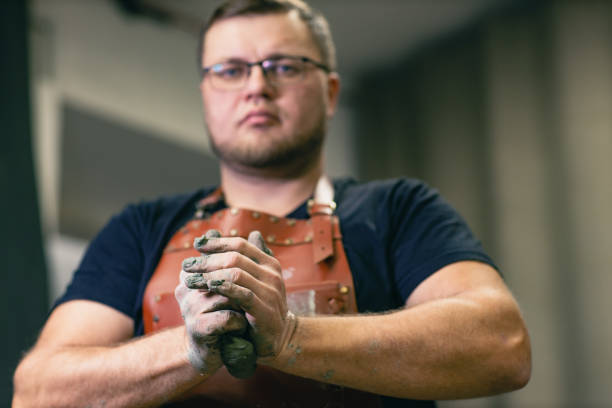 Man sculptor dressed leather apron with clay in hands. Statue craft creation workshop.