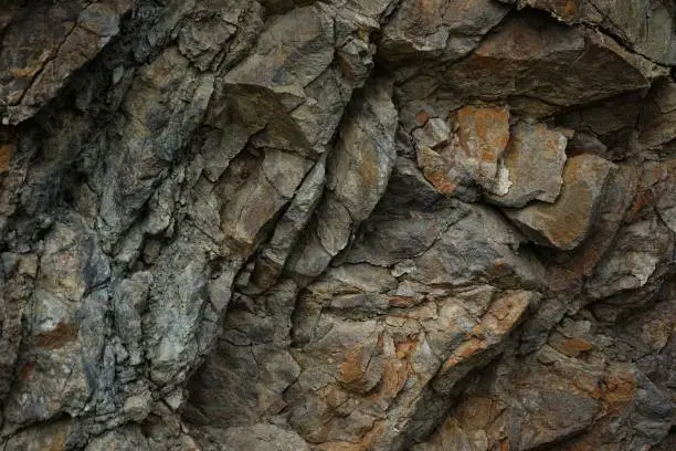 Photo of Stone rock mountain cave granite basalt mineral surface texture background. Dark gray brown beige. Crack broken crumbled crushed. Close-up. 3d.