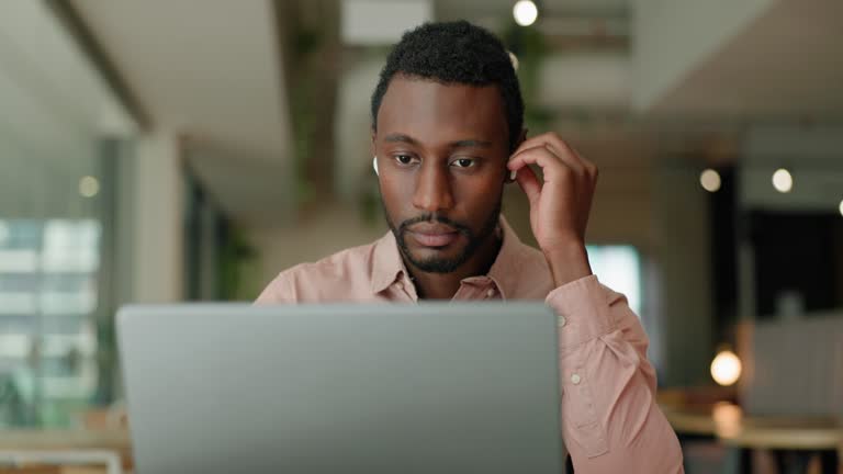 Laptop, earphones and business black man in office for streaming music, webinar and online videos. Corporate, professional and person on computer for internet listening to podcast, radio and audio