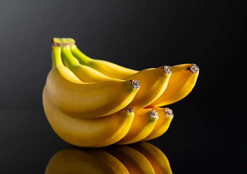 Bunch of ripe bananas on a black reflective background.