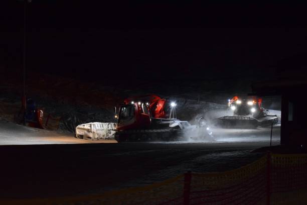 istock Two snow groomers compacting ski runs at night 2009034324