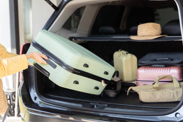 istock Woman loading suitcase into car trunk, preparation for trip.  Open car boot packed for family vacation. Young beautiful woman travel concept. 2009086656