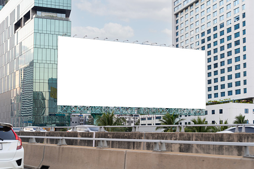 Large horizontal blank sign on a highway in Bangkok, Thailand. Traffic and sky, clipping path. A blank billboard with an elevated highway in the background.
