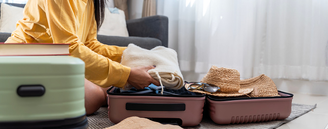 Travel packing, above and hands of a woman with clothes, holiday luggage and prepare for international summer. Suitcase, ready and person traveling with a suitcase, vacation clothing and hotel bag