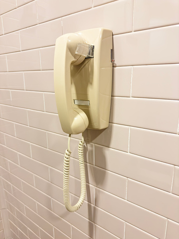 Old fashioned wall phone on a tiled wall