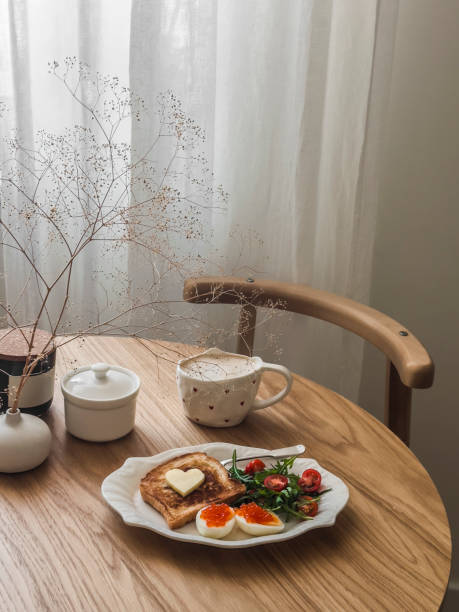 istock Romantic Valentine's Day breakfast, brunch - coffee, toast, eggs with red caviar and salad on a round wooden table 2009401857