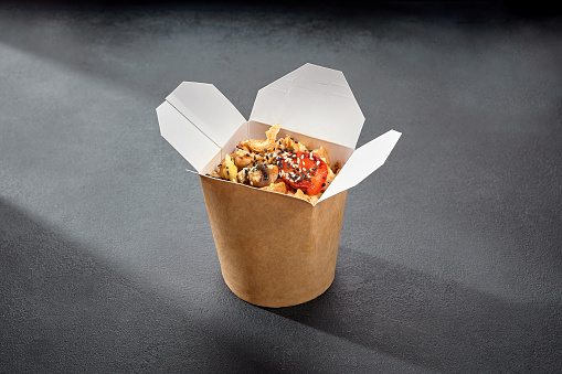 Stir-fried rice with chicken and vegetables in a wok, served in a takeaway box, ideal for a fast and fulfilling Asian-inspired meal.