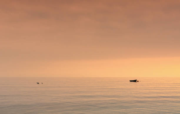 istock small boat at anchor in a calm ocean at sunset 2009429066
