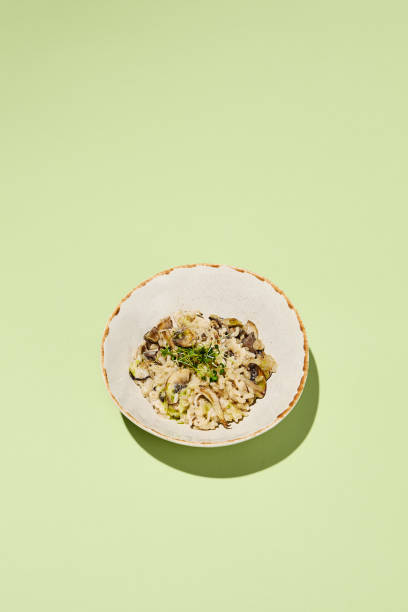 istock Mushroom risotto with truffle oil, elegantly served on artisanal tableware, highlighted by a harmonious green background for a luxury meal experience 2009439565