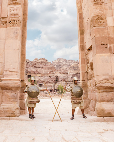 Wadi Musa, Jordan, October 05, 2023 : Two Bedouins dressed in the military uniform of the ancient Nabateans guard the passage between the columns in Nabatean Kingdom of Petra in Wadi Musa city in Jordan