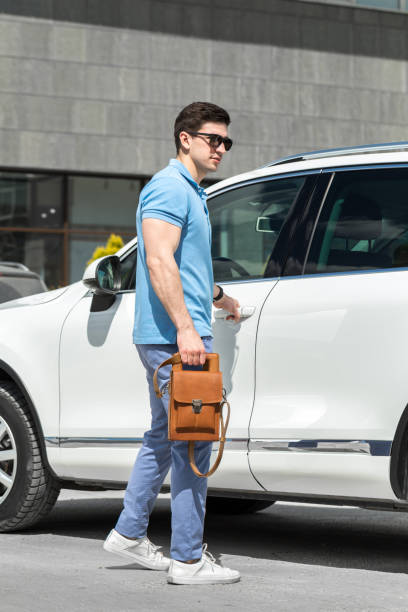 istock Young man with brown leather bag standing near the car 2009509326