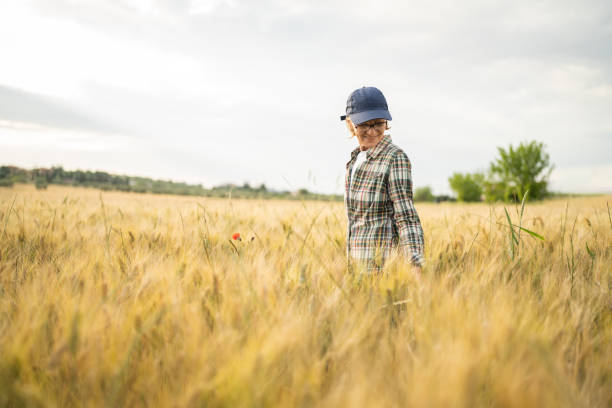 Satisfied female farmer walking in wheat field and checking the state of wheat culture