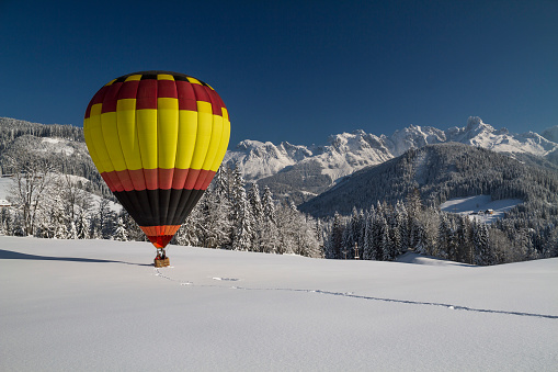 A vibrant hot air balloon above snowy mountains