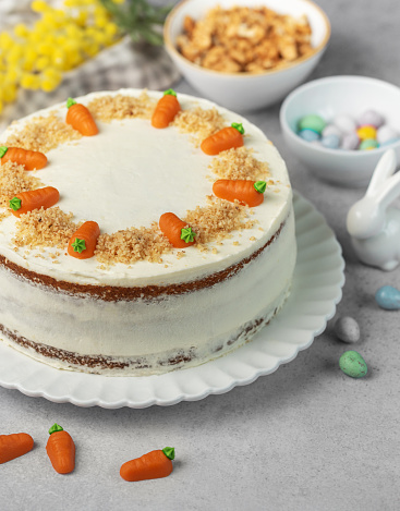 Homemade Easter carrot cake made with walnuts, iced with cream cheese. Sweet dessert.  Plate with delicious carrot cake