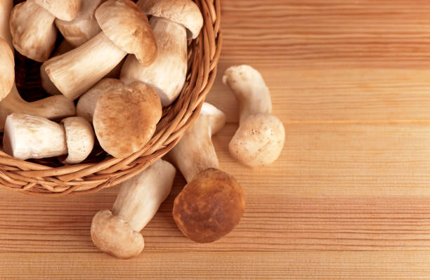 raw white mushrooms in basket on wooden table