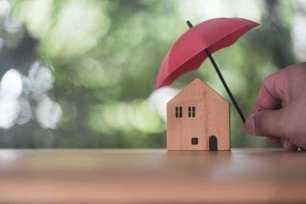 istock Individuals holding small red umbrellas and model homes. Insurance is risk control 2009619538