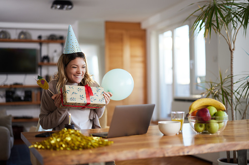Happy woman celebrating her Birthday while talking to someone through video call at home.