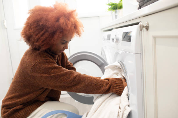 istock Young woman loading clothes into a washing machine 2009650602