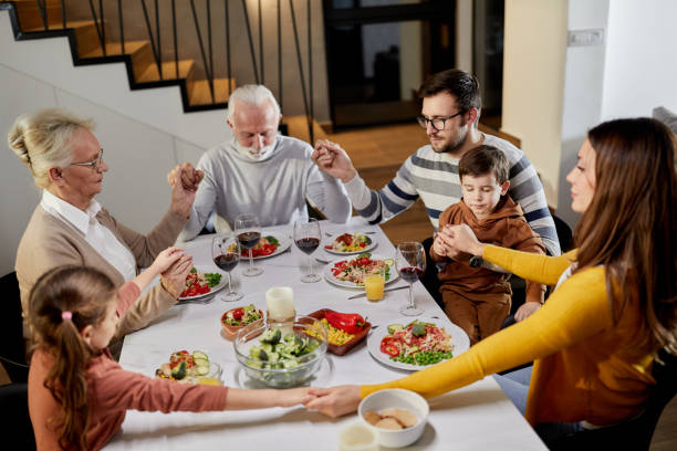 istock Extended family praying before lunch in dining room. 2009651206