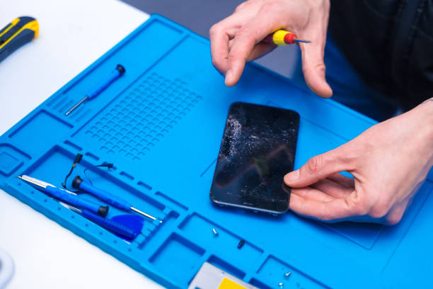 istock Repairman opening a phone with a screwdriver in a workshop 2009673567