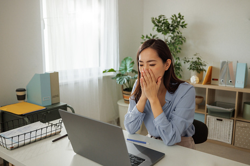 Frustrated woman having video call while using laptop at home office