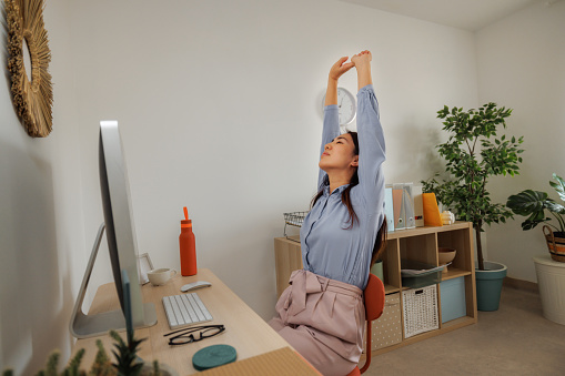 Woman stretching while working at home office