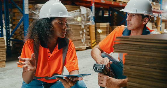 Young African American black woman and caucasian man warehouse worker checks stock and check merchandise package using barcode scanner in factory warehouse. Logistic industry business concept.