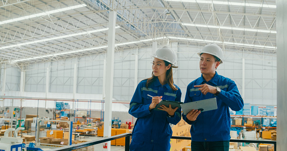 Professional Asian male and female industrial engineers discuss new project in manufacturing factory. Working in manufacturing plant or production plant concept.