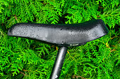 Close-up of a wet old blacl leather bicycle saddle isolated