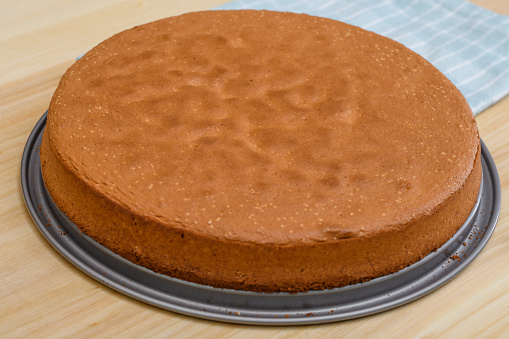A baked round brown sponge cake lies on the table