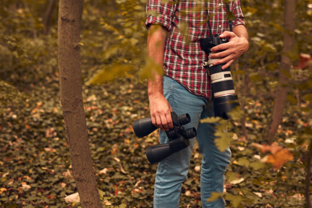 istock Man using binoculars and camera for birdwatching and other observing animals in nature. 2009709095